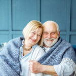 Lovele senior couple wrapped with plaid at home