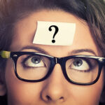 Woman thinking looking at junk food and vegetables shaped as lig