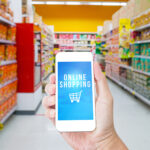 Hand holding  mobile phone  with Online shopping word with blur suppermarket  background,Business solution concept