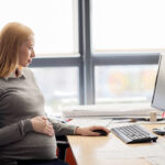 pregnant businesswoman with computer at office